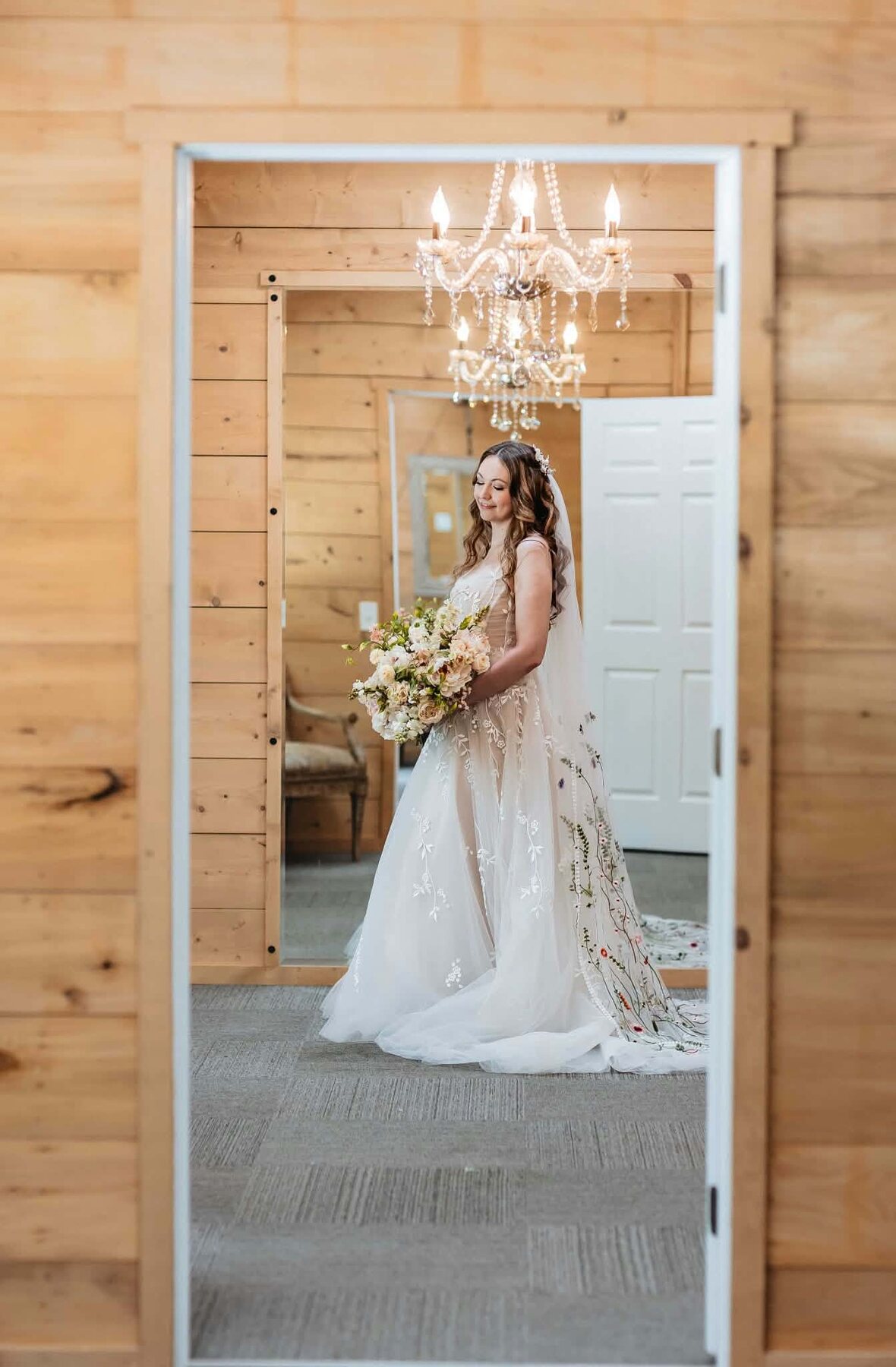 Bride holding her bouquet under a chandelier while getting ready