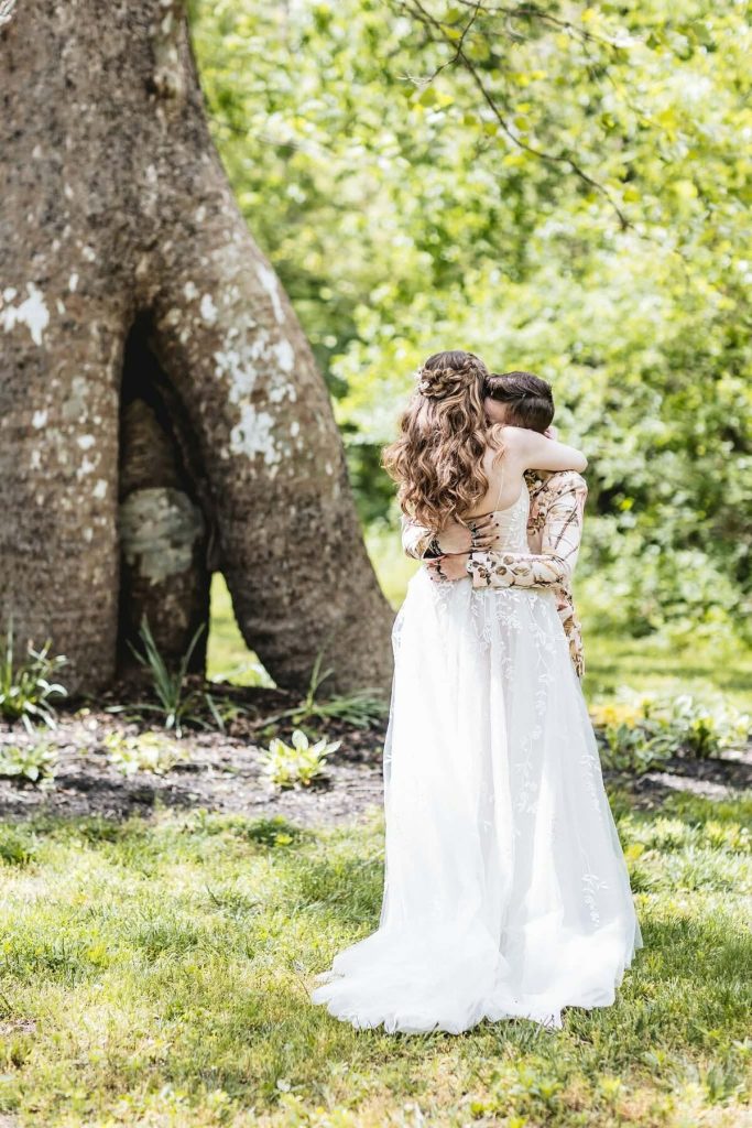 First look hug under a large tree before an Indiana wedding